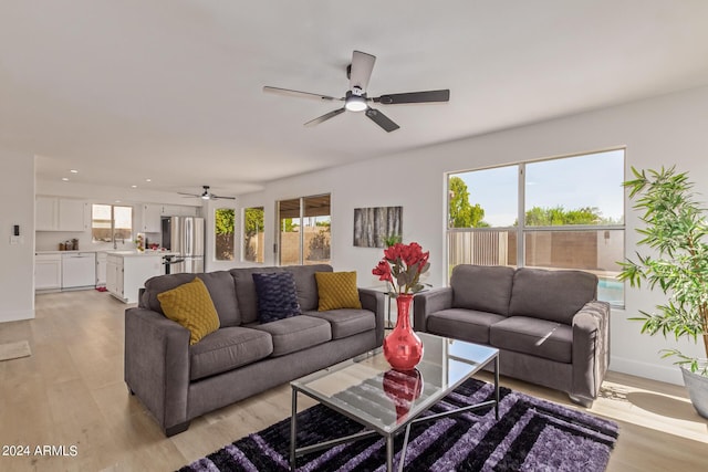 living room with sink, light wood-type flooring, and ceiling fan