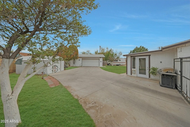 exterior space featuring an outbuilding, driveway, a patio, fence, and a yard