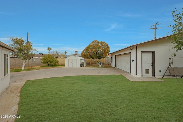 view of yard featuring an outdoor structure, a fenced backyard, a garage, and a shed