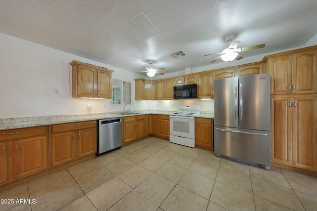 kitchen with light stone counters, a ceiling fan, visible vents, a sink, and appliances with stainless steel finishes