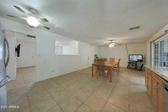 dining space featuring light tile patterned floors, a ceiling fan, visible vents, and a textured ceiling