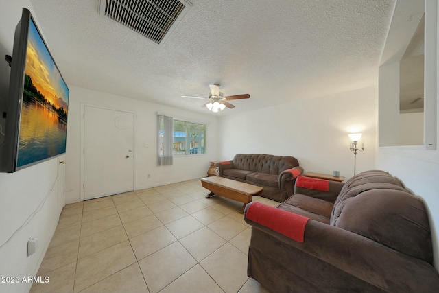 living room with light tile patterned flooring, visible vents, a textured ceiling, and ceiling fan