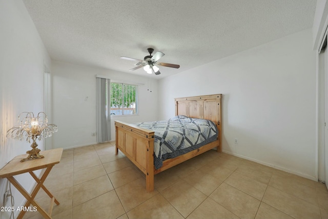 bedroom featuring light tile patterned floors, baseboards, a textured ceiling, and ceiling fan