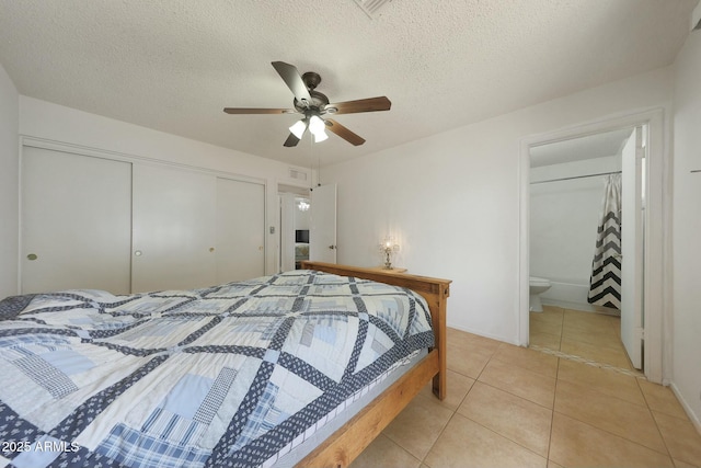 bedroom with a closet, light tile patterned floors, connected bathroom, and a textured ceiling