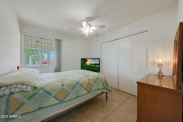 bedroom with ceiling fan, light tile patterned flooring, a closet, and a textured ceiling