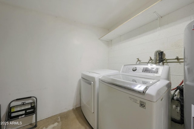 laundry room featuring laundry area, concrete block wall, and separate washer and dryer