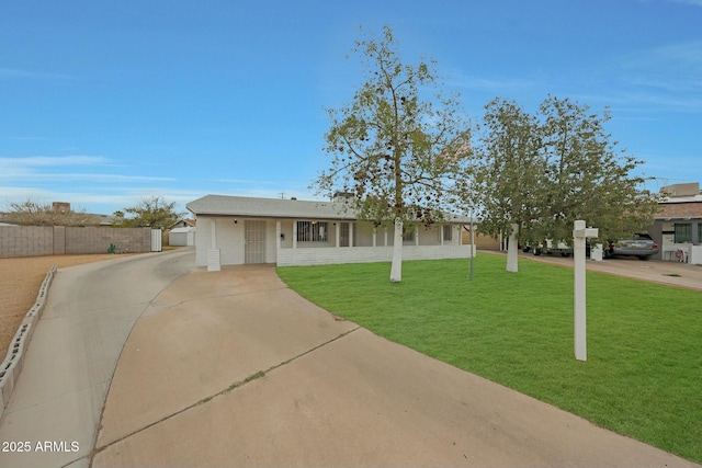 ranch-style house with a front yard, fence, and driveway