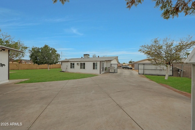 back of property featuring a lawn, driveway, a garage, and fence