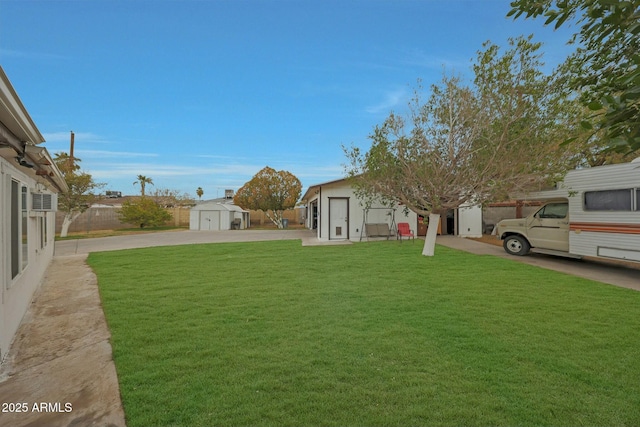 view of yard with a storage shed, an outbuilding, and fence