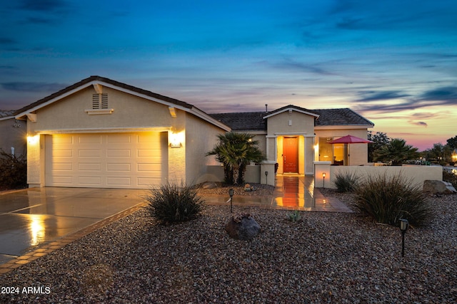 ranch-style home with a garage, concrete driveway, fence, and stucco siding