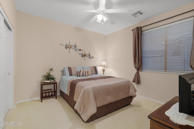 bedroom with light carpet, a ceiling fan, visible vents, baseboards, and a closet