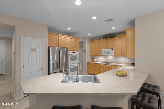 kitchen with a peninsula, white appliances, a breakfast bar area, and a sink