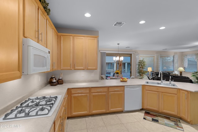 kitchen with a peninsula, white appliances, light countertops, and a sink