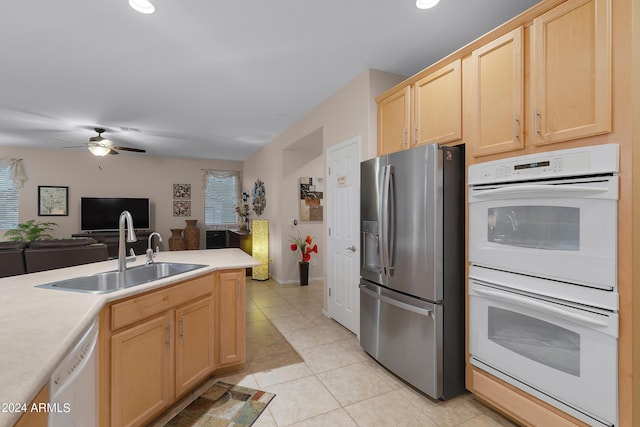 kitchen featuring light brown cabinets, white appliances, a sink, open floor plan, and light countertops