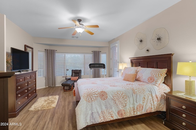 bedroom with ceiling fan, visible vents, and wood finished floors