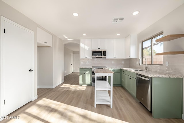 kitchen with appliances with stainless steel finishes, sink, light hardwood / wood-style flooring, green cabinetry, and white cabinets