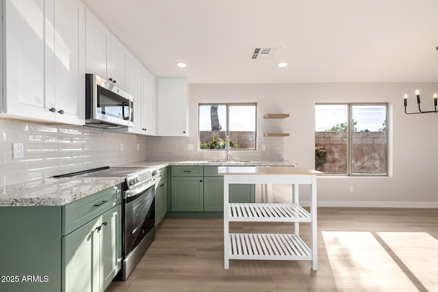 kitchen featuring sink, green cabinetry, light wood-type flooring, appliances with stainless steel finishes, and white cabinetry