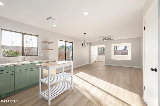 kitchen featuring plenty of natural light, green cabinets, light wood-type flooring, and sink