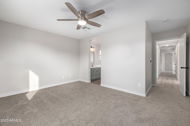 unfurnished bedroom featuring light carpet, ensuite bath, ceiling fan, and sink