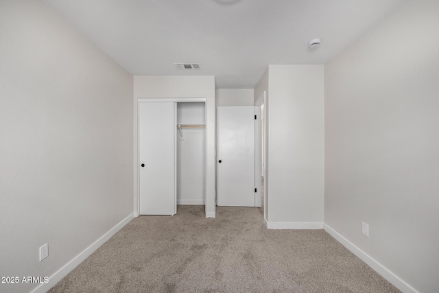 unfurnished bedroom featuring a closet and light colored carpet