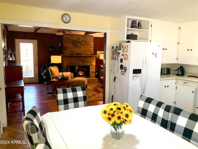 dining room featuring dark wood-type flooring, wooden walls, and a large fireplace