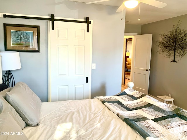 bedroom with ceiling fan and a barn door