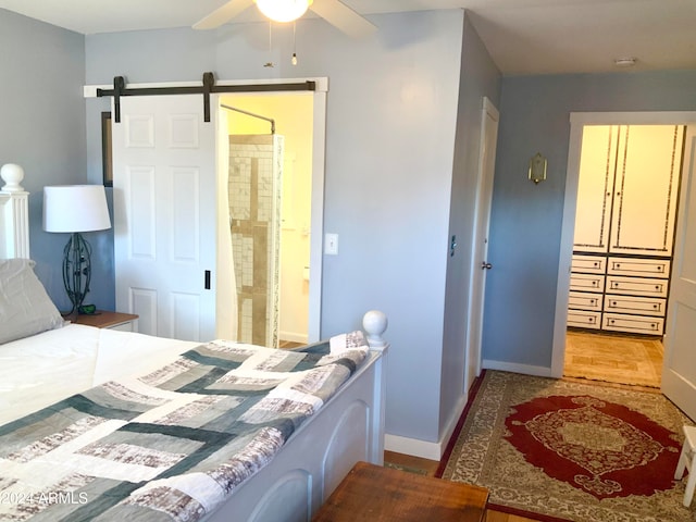 bedroom featuring ensuite bath, a barn door, and ceiling fan