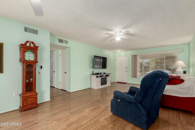 sitting room with visible vents, a textured ceiling, wood finished floors, and a ceiling fan