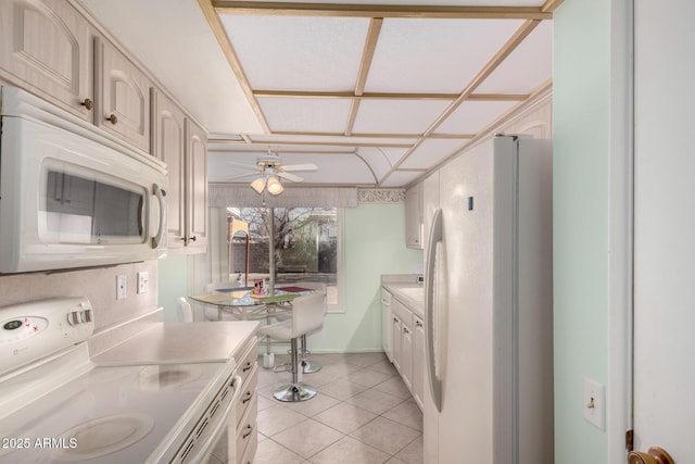 kitchen featuring a ceiling fan, white appliances, light countertops, light tile patterned floors, and baseboards