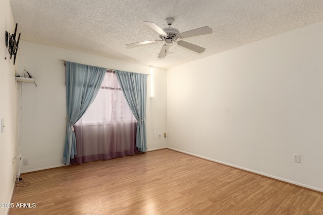 unfurnished room featuring ceiling fan, light wood-style flooring, baseboards, and a textured ceiling