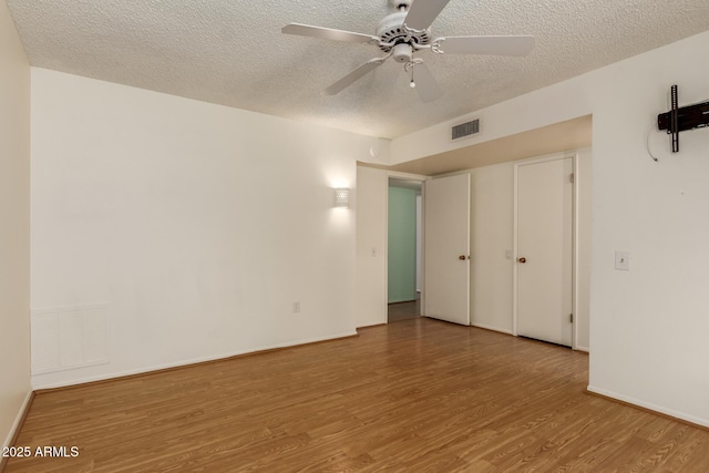 unfurnished bedroom with baseboards, wood finished floors, visible vents, and a textured ceiling