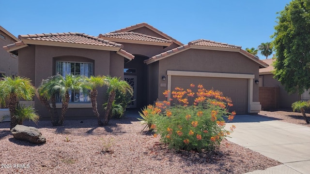 mediterranean / spanish house featuring concrete driveway, a tiled roof, a garage, and stucco siding