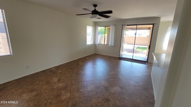 spare room with dark tile patterned floors and ceiling fan