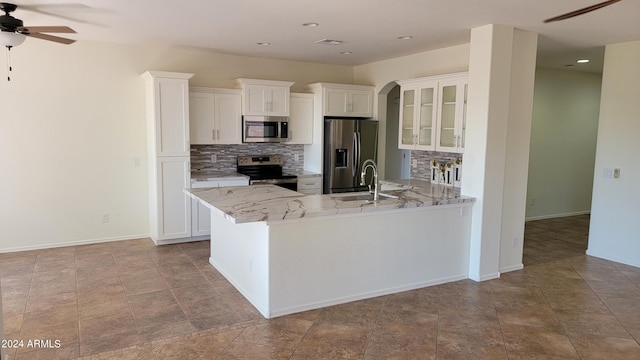 kitchen featuring appliances with stainless steel finishes, sink, decorative backsplash, white cabinetry, and ceiling fan