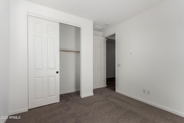 unfurnished bedroom with a closet and dark colored carpet