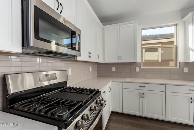 kitchen featuring backsplash, white cabinets, dark wood-type flooring, and appliances with stainless steel finishes