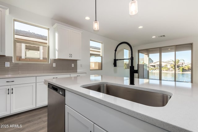 kitchen featuring decorative light fixtures, white cabinetry, sink, light stone counters, and stainless steel dishwasher