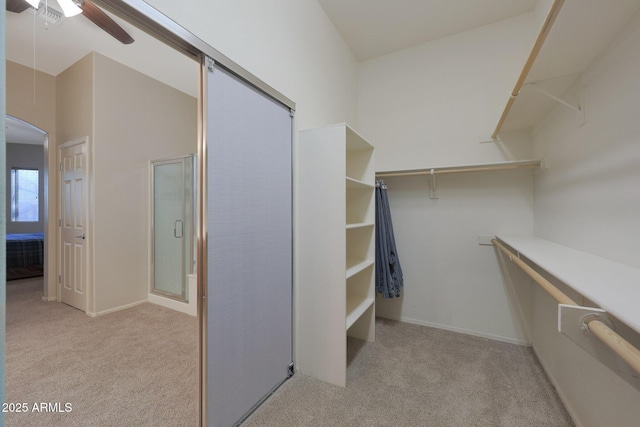 walk in closet featuring ceiling fan, light colored carpet, and vaulted ceiling