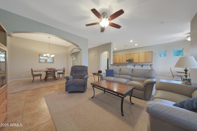 tiled living room with ceiling fan with notable chandelier