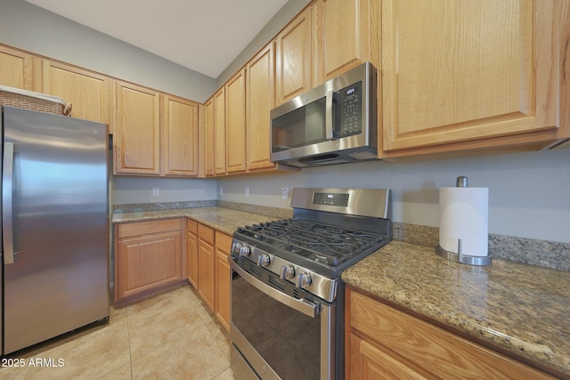 kitchen featuring light stone countertops, appliances with stainless steel finishes, light tile patterned floors, and light brown cabinetry