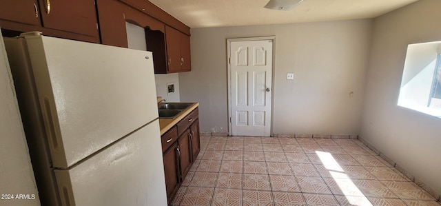 kitchen with sink, light tile floors, and white fridge