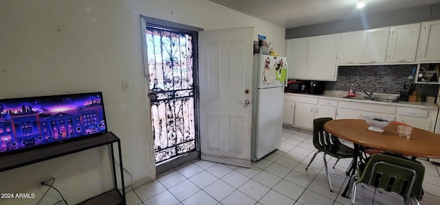 kitchen with white cabinets, light tile flooring, backsplash, white fridge, and sink