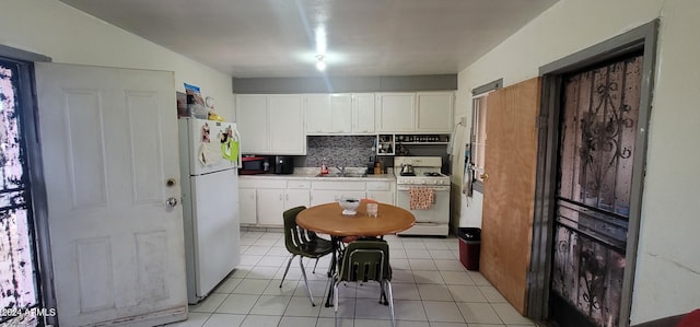 kitchen featuring white appliances, tasteful backsplash, white cabinets, sink, and light tile floors