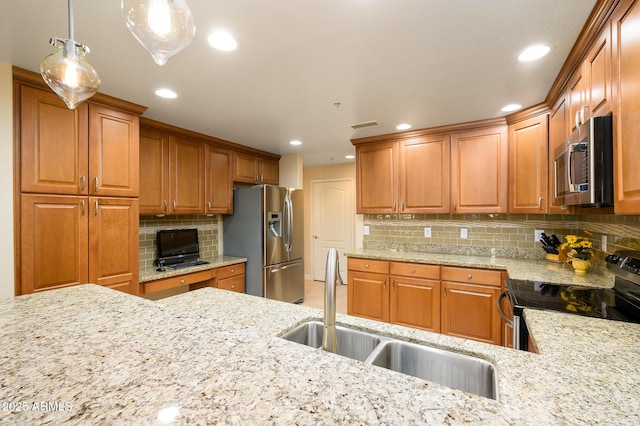 kitchen with appliances with stainless steel finishes, hanging light fixtures, light stone counters, and sink