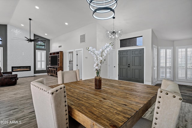 8913 S Forest Ave, Tempe, AZ 85284 - dining room featuring a ceiling fan, wood finished floors, a chandelier, a fireplace, and high vaulted ceiling