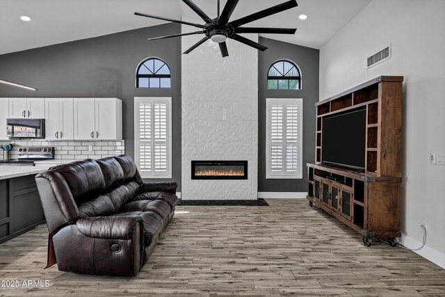 8913 S Forest Ave, Tempe, AZ 85284 - living room featuring ceiling fan, high vaulted ceiling, light wood finished floors, a tile fireplace, and recessed lighting