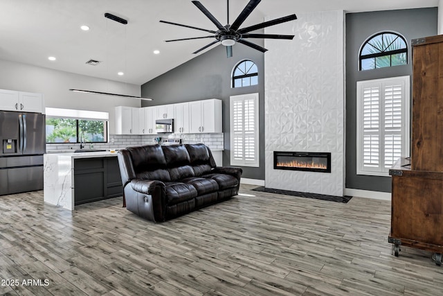 8913 S Forest Ave, Tempe, AZ 85284 - living room featuring high vaulted ceiling, ceiling fan, light wood-style floors, a large fireplace, and recessed lighting