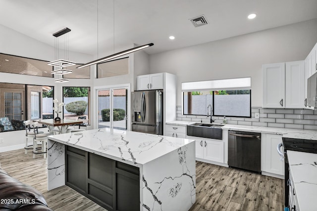 8913 S Forest Ave, Tempe, AZ 85284 - kitchen featuring dishwashing machine, stainless steel fridge with ice dispenser, a sink, light wood-style flooring, and light stone countertops