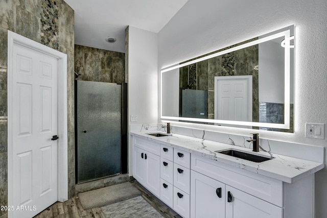 8913 S Forest Ave, Tempe, AZ 85284 - bathroom featuring double vanity, a stall shower, wood finished floors, and a textured wall