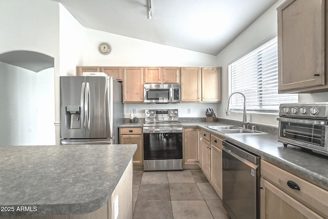 kitchen with vaulted ceiling, dark countertops, stainless steel appliances, and a sink